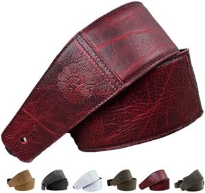 Deep red full grain leather guitar strap attached to an electric guitar in a studio setting.